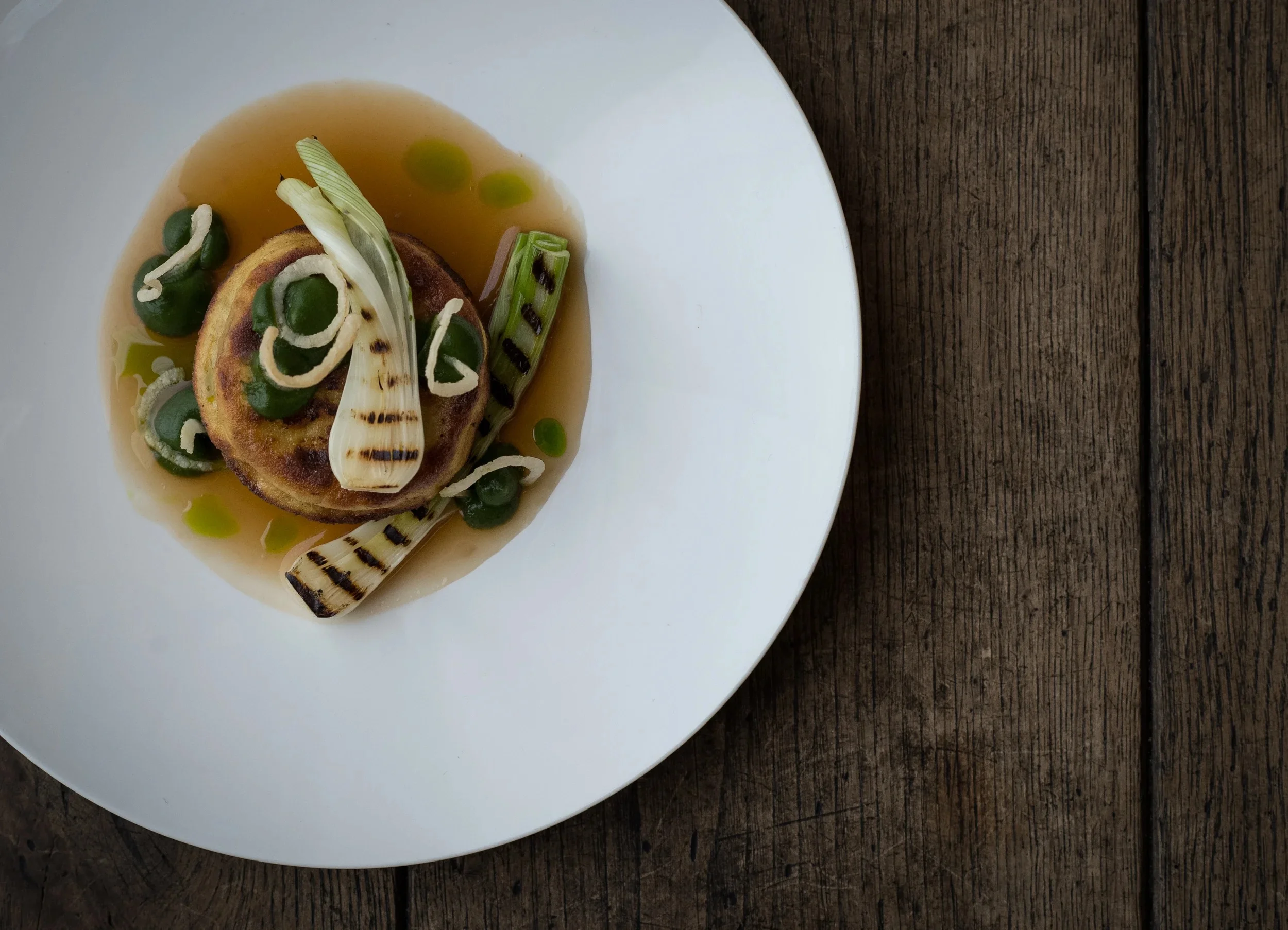 Top-down plating of an appetizer with grilled fennel and purees.